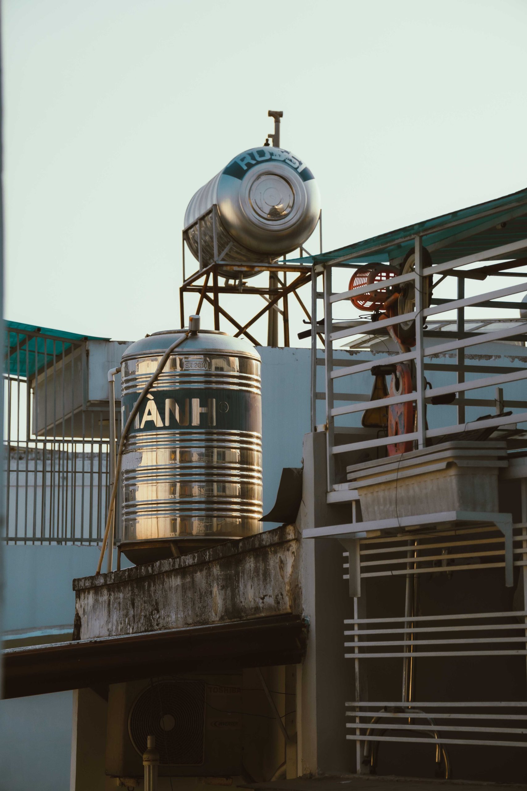 Rooftop water tanks with urban architecture in Ho Chi Minh City under a clear sky.